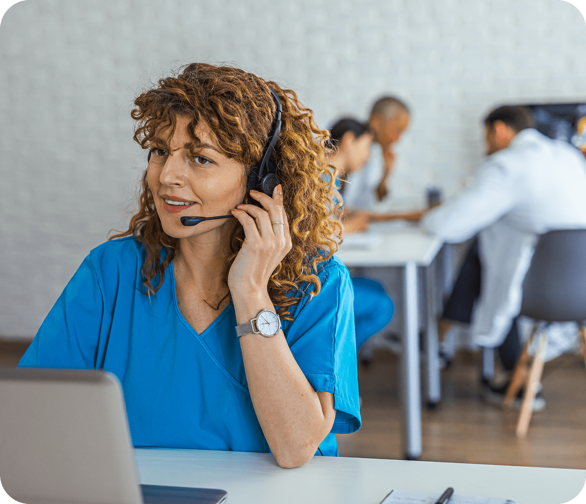 Healthcare professional with headset at a desk.