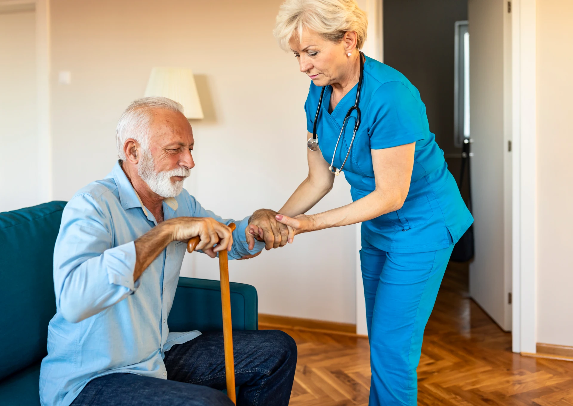 Caregiver helping elderly man with cane.