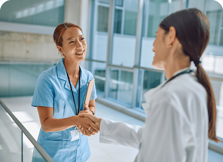 Two healthcare professionals shaking hands, smiling.