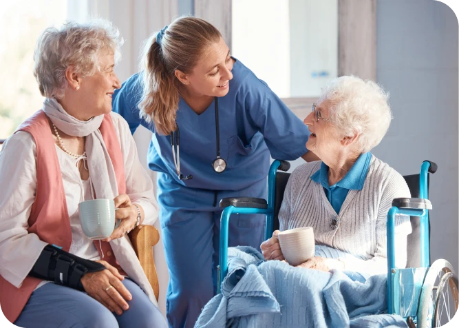 Nurse interacting with elderly women in wheelchairs.